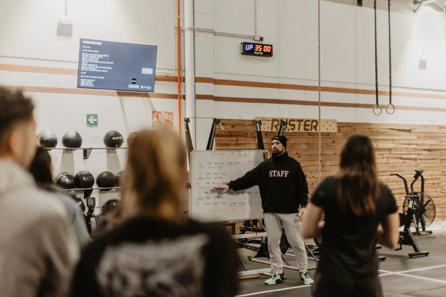 Coach explicant el WOD a la pissarra amb atletes escoltant