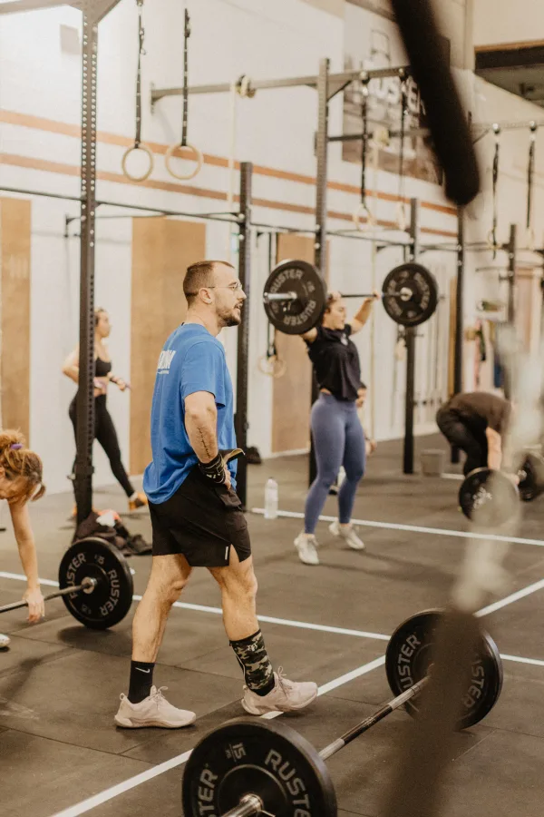 Grup d'atletes amb barres olímpiques durant classe Strength Club